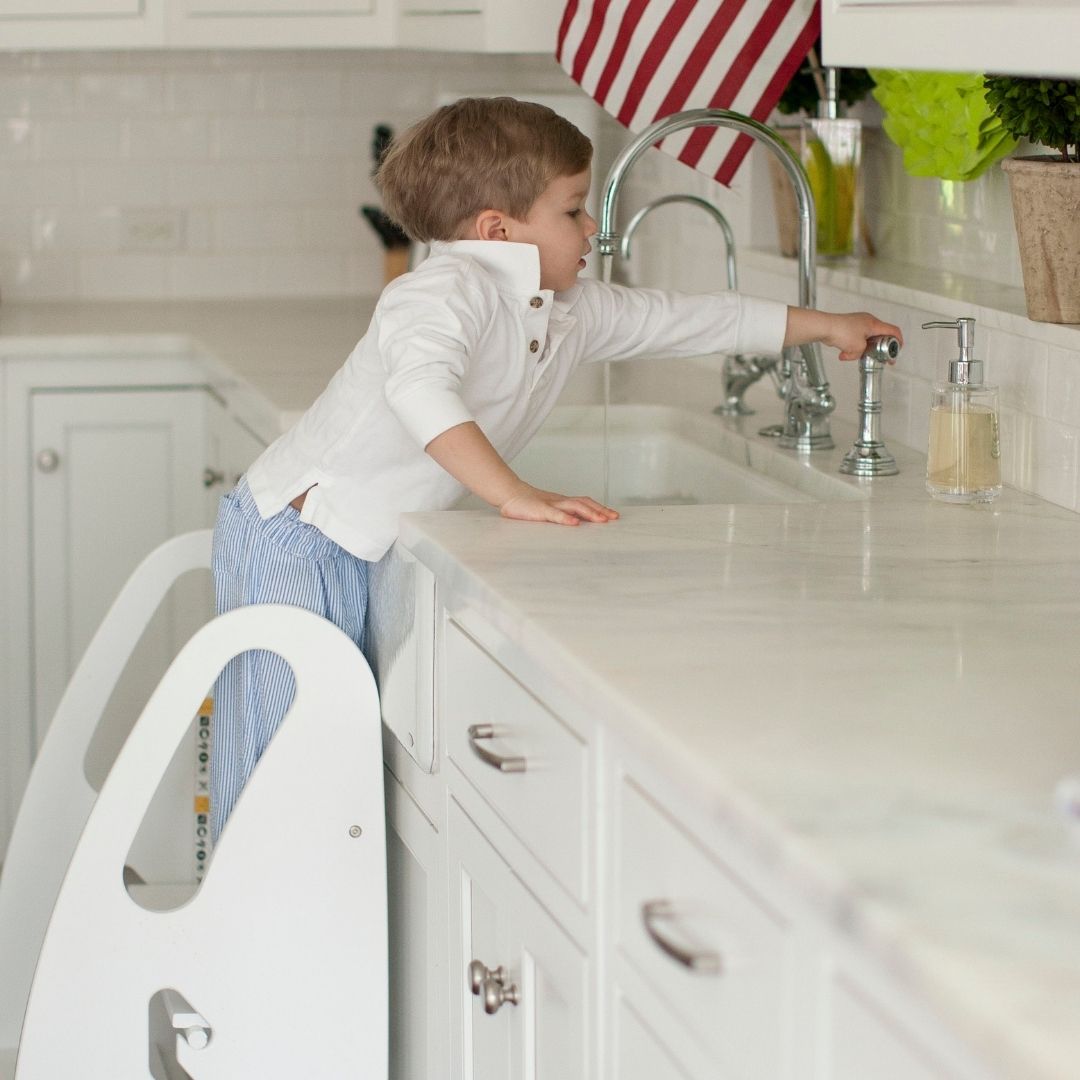 A young boy stands at the kitchen sink in the 3-in-1 Growing Step Stool.