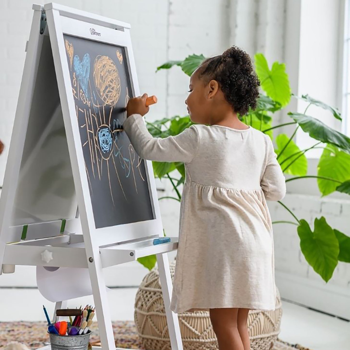 A young girl is drawing on the Artist EZ Easel with chalk.