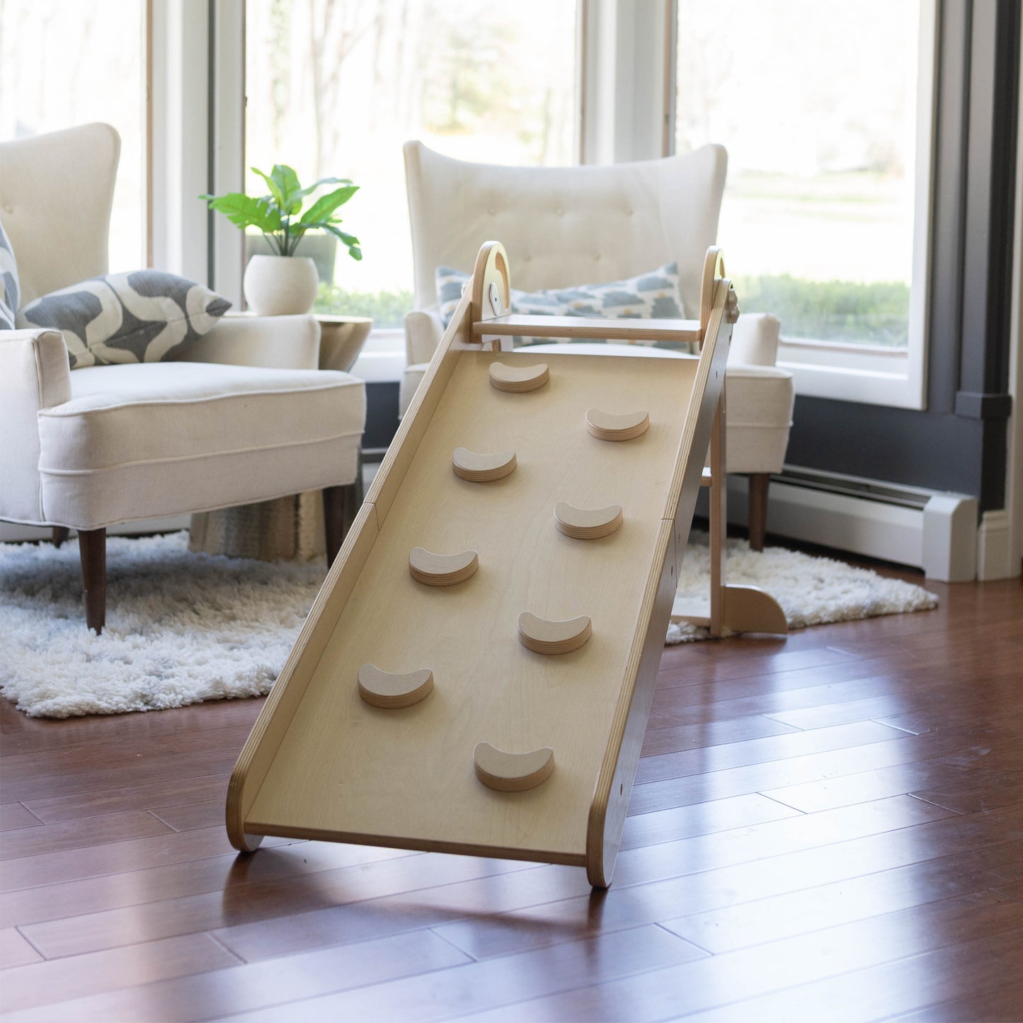 The 2-in-1 Folding Learn N Slide is sitting in a living room.  The ramp side of the slide is showing.