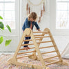 A young girl is climbing on the Learn N Climb Triangle.