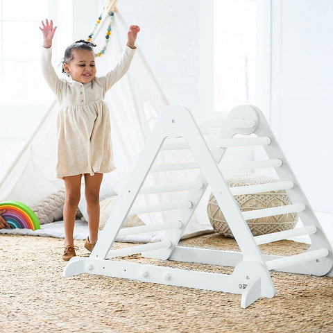 A young girl is standing next to the Learn N Climb Triangle in Soft White Color.