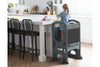 A young girl stands at the kitchen counter in the Limited Edition Learning Tower in Earl Grey color. 