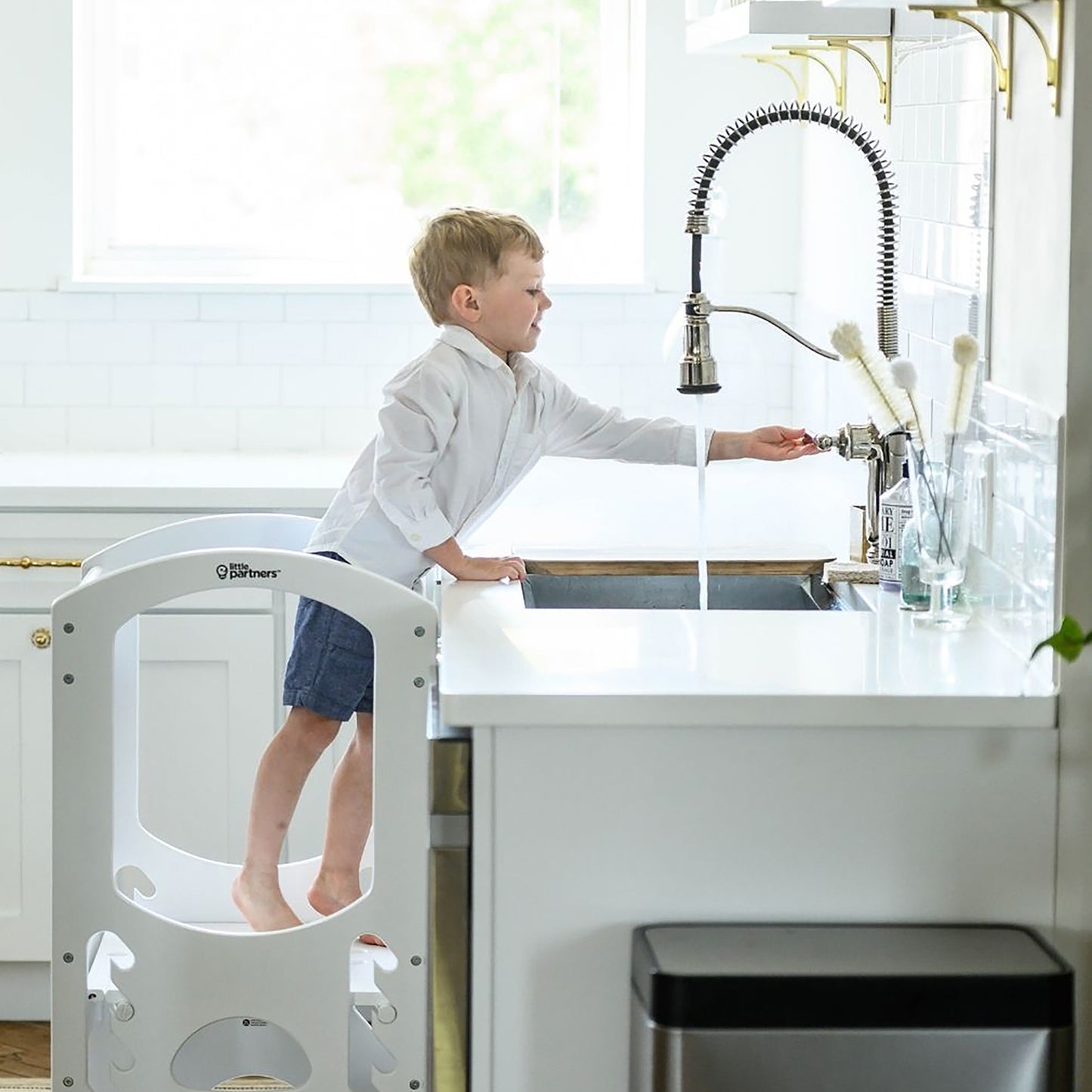 A young boy stands at the Kitchen sink in The Learning Tower.