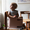 A young girl is sitting in the 3-in-1 Learning Booster and Step Stool.