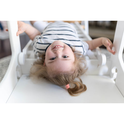 A young girl is laying down on the Climbing Ladder, which is connected to The Learning Tower.