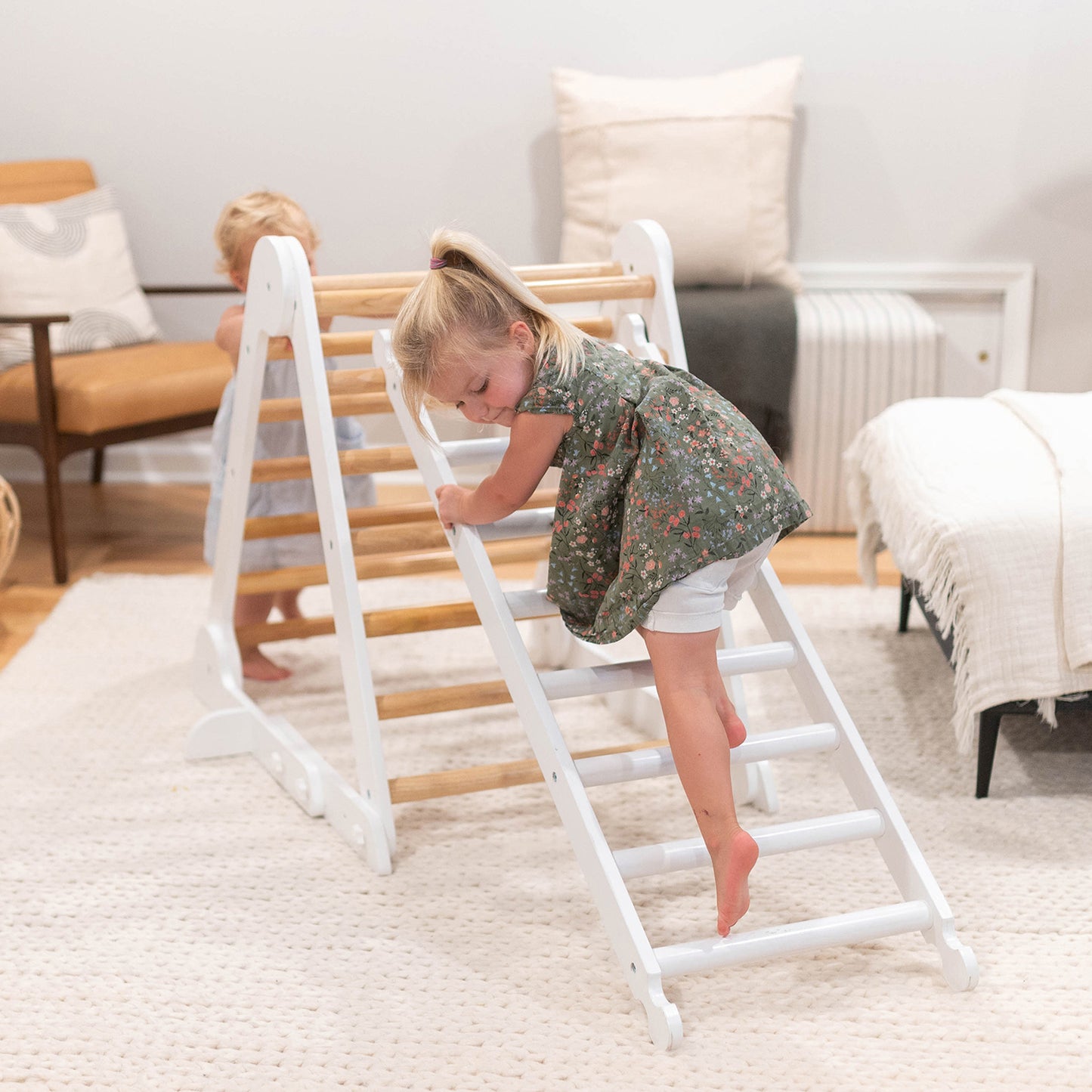 A young girl is climbing on the Climbing Ladder while it is securely attached to the Climbing Triangle.